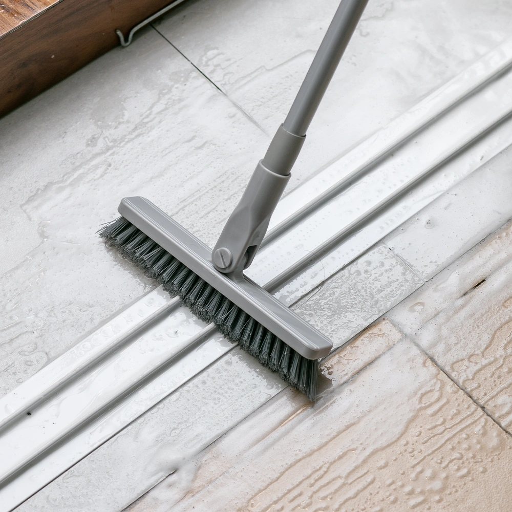 A brush that is currently cleaning the gaps between sliding doors on the floor